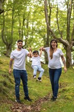 Vertical photo of a family playing while walking along a forest