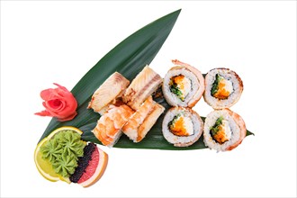 Overhead view of roll with flying fish caviar with cream cheese and shrimp on top served on bamboo leaves