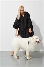 Happy blonde woman with fluffy samoyed dog