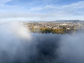 Aerial view of the town of Radolfzell on Lake Constance with autumn vegetation and drifting fog over the lake