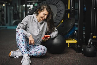 Athletic smiling woman with smartphone gym