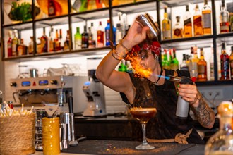 Bartender using torch to flaming the decoration of a cocktail