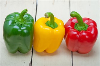 Three fresh bell peppers over old wood table