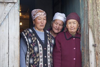Three Kyrgyz women posing in doorway of house at village Sary-Tash