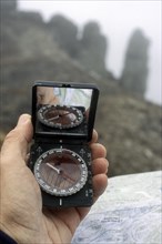 Hiker reads compass and topographic map for orientation in the fog in the mountains