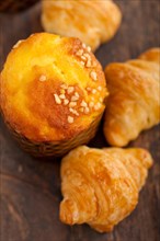 Fresh baked muffin and croissant mignon on old wood table