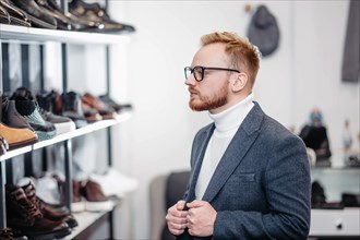 Business successful man businessman in glasses chooses shoes for himself in a shoe store