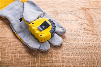 Yellow measuring tape on the front of the protective glove and the wooden board