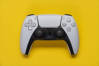 Controller of the PS5 Playstation game console from Sony in front of a monochrome yellow background