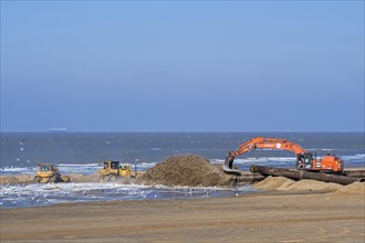 Bulldozers and hydraulic excavator installing pipeline during sand replenishment