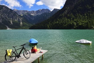 Cyclist taking a break on a wooden footbridge at Plansee