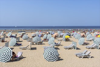 Sunbathers in relax chairs under parasols on the beach at seaside resort along the Belgian North Sea coast during heat wave in summer in Belgium
