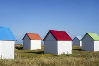 Row of colourful beach cabins in the dunes at Gouville-sur-Mer