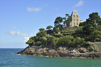 Typical house at Dinard and tourists walking along the sea