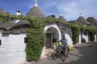 Cyclist between trulli in Alberobello