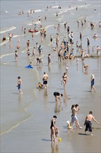 Tourists in swimsuits paddling and swimming in water during the summer holidays along the North Sea coast