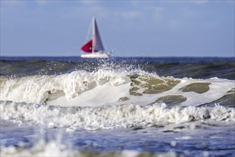 Wave breaking on the beach and sailing boat