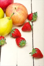Fresh fruits apples pears and strawberry on a white wood table