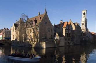 Belfry and tourists taking a sightseeing boat trip on the canals of Bruges