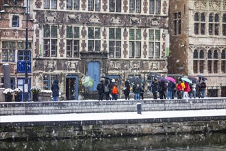 Guided tour with tourists visiting the city Ghent during snow shower in winter