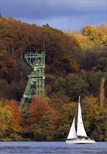 A sailing boat in autumn with the foerdegeruest of the Carl Funke colliery
