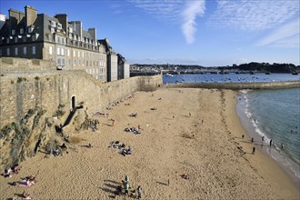 Tourists sunbathing on beach in front of rampart at Saint-Malo
