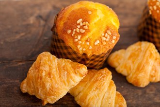 Fresh baked muffin and croissant mignon on old wood table