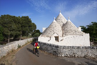 Cyclist between trulli near Noci
