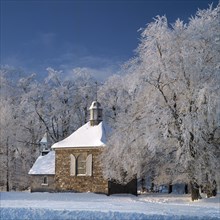 The Fischbach chapel and trees covered in snow in winter at Baraque Michel