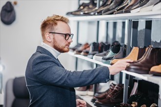 Business successful man businessman in glasses chooses shoes for himself in a shoe store