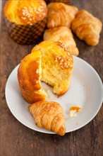 Fresh baked muffin and croissant mignon on old wood table