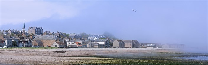 Shingle beach covered in mist and the town Stonehaven