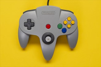 Controller Nintendo 64 game console in front of monochrome yellow background