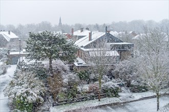 View over houses and gardens in suburban residential area during unexpected late snow shower in March 2023