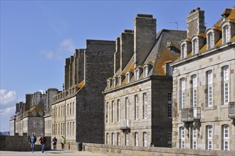 Tourists walking on the town ramparts and typical houses at Saint-Malo