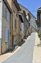 Steep street with houses with window shutters at Auch