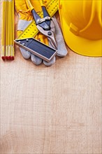 Construction helmet Protective glove Square ruler Wooden metre tongs on oak board Construction concept