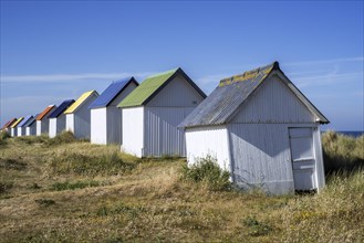 Row of colourful beach cabins in the dunes at Gouville-sur-Mer