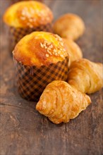 Fresh baked muffin and croissant mignon on old wood table