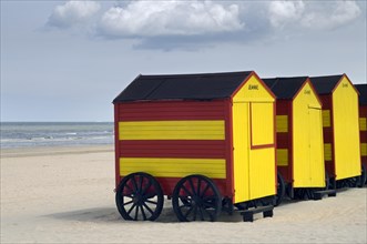 Row of colourful striped beach cabins on wheels along the North Sea coast at seaside resort De Panne