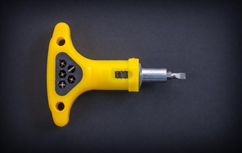 Aerial view of yellow hand screwdriver on black background