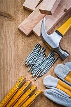 Composition of carpentry tools nails wooden metre protective glove claw hammer planks on wooden board