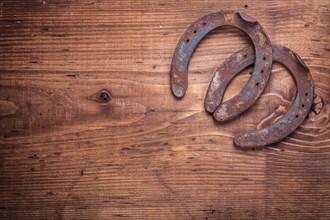 Copyspace image two old cast iron metal western horse shoeing accessories horseshoes on antique wooden background happy concept