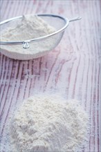 Flour in sieve on vintage wooden board Food and drink concept