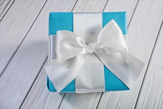 Gift box with white ribbon and bow on painted panels