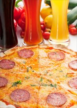Italian original thin crust pepperoni pizza with selection of beers and vegetables on background