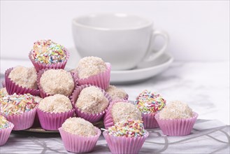 Light rum balls in pink paper cups with colourful sprinkles and coconut