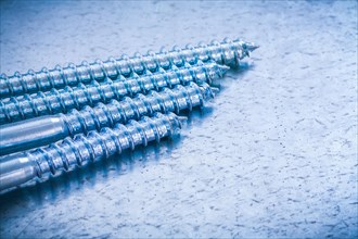 Group of metal threaded bolts on a metallic background Design concept
