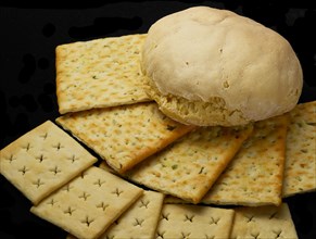 Fresh bread and crackers on black background