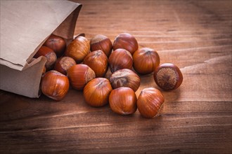 Hazelnuts and paper bag on vintage wooden board Food and drink still life